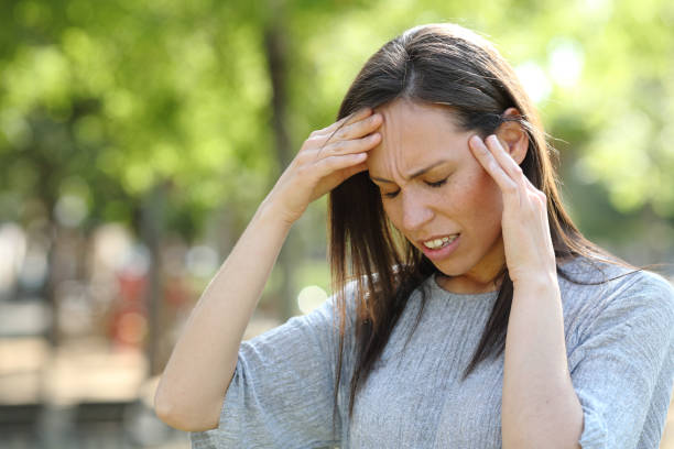 istock Woman suffering head ache outdoors in a park 1155215289