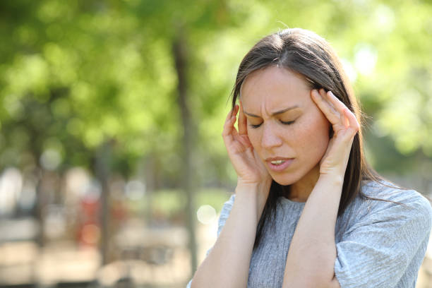 istock Woman suffering migraine outdoors in a park 1155215295