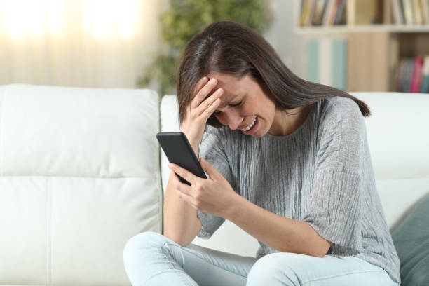 istock Sad woman at home checking smart phone 1155215399