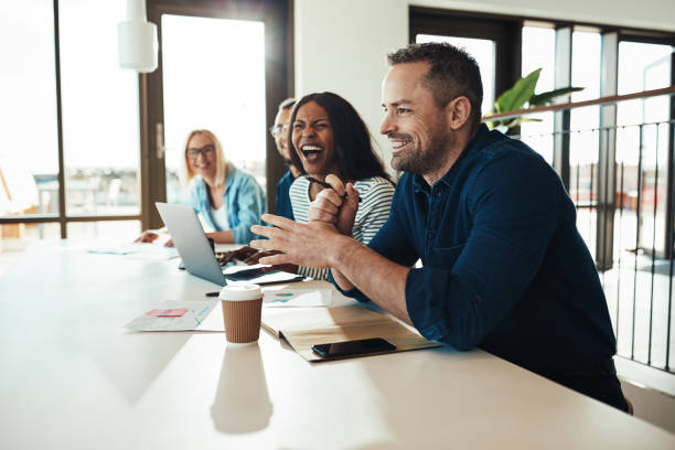 istock Businessman laughing with a group of office colleagues at work 1155216797