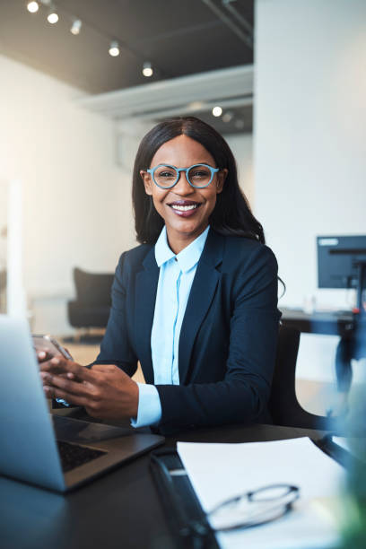 istock Smiling African American businesswoman sitting at work using a cellphone 1155217196