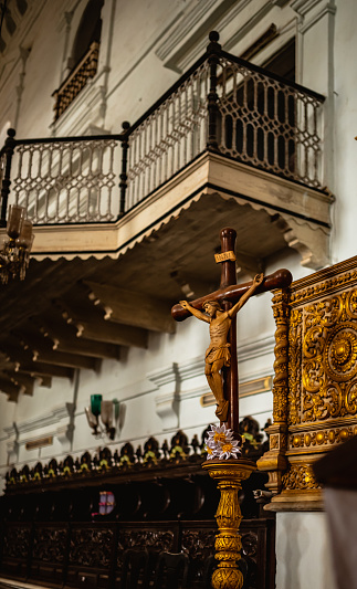 A small wooden cross with jesus statue on a gold stand. Small vintage balcony at the center stage of the church.