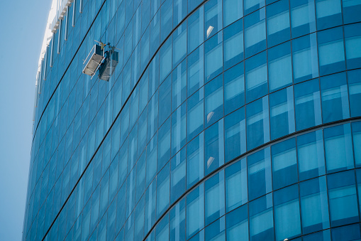 Window cleaner working high up on the exterior of a glass skyscraper in Perth.