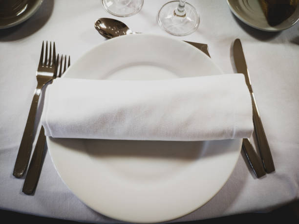 istock Napkin on an empty round white plate with cutlery on the sides on a white table 1155225499