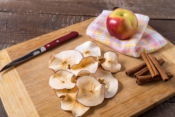 istock Dried apple chips , raw apple , cinnamon sticks on cooking board over wood background. 1155226037