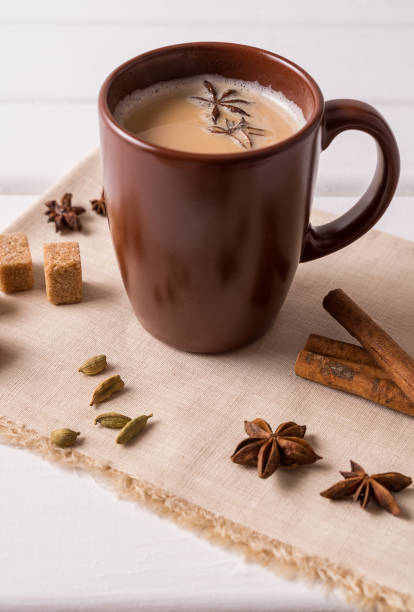istock Masala chai tea in a mug and kitchen herbs, over white table background. 1155226069