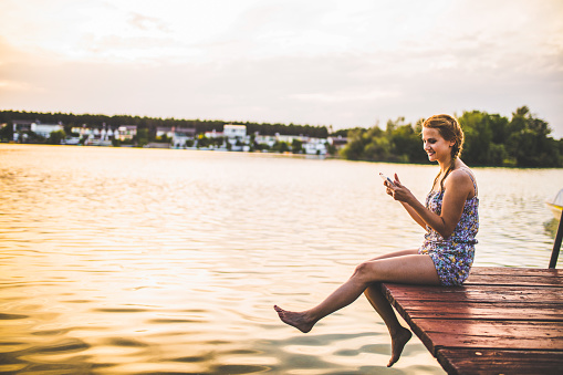 Woman using internet technology by lake
