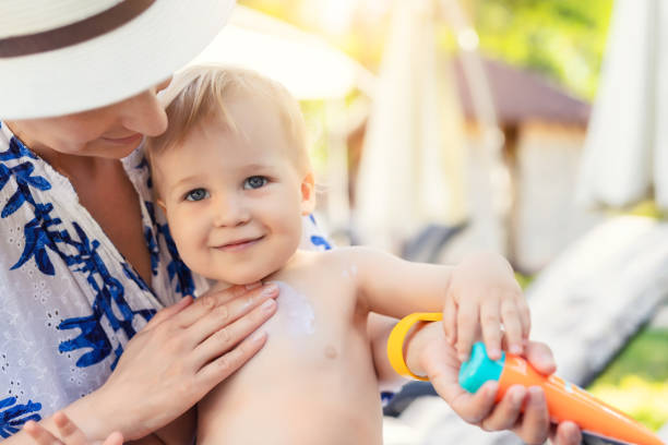 かわいい幼児の男の子の顔に日焼け止め保護クレームを適用する母親。夏の海の休暇中に太陽から赤ちゃんを保護するために sunblocking ローションを使用してママ。旅行時の子供のヘルスケア - child beauty mother little boys ストックフォトと画像