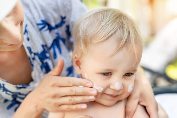 Mother applying sunscreen protection creme on cute little toddler boy face. Mom using sunblocking lotion to protect baby from sun during summer sea vacation. Children healthcare at travel time stock photo