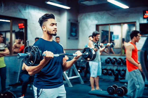India, Fitness, Healthy Lifestyle - Indian man lifting weights at a fitness centre