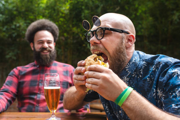 istock Hungry hipster man eating a tasty burger while sitting at a local restaurant 1155232218
