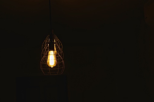 Old light bulb hanging on ceiling with copy space