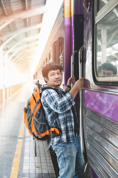 istock Asian man traveler with backpack is stepping up the train in train station. 1155236527