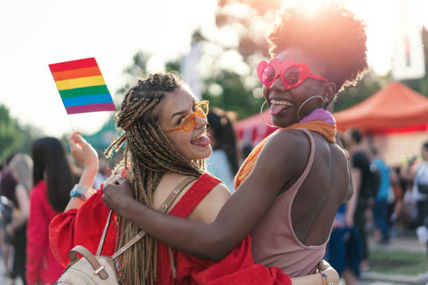 istock Young female couple walking with the pride parade 1155237464