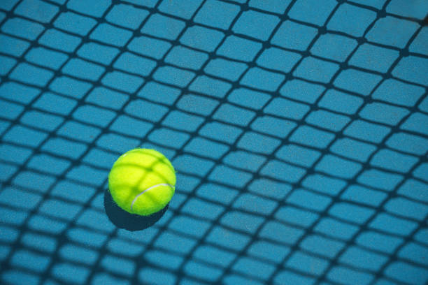 Summer sport concept with tennis ball and net on hard tennis court. Summer sport concept with tennis ball and net on hard tennis court. Flat lay, top view, copy space. harsh shadows stock pictures, royalty-free photos & images