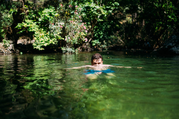 istock Young Man Swims in the River 1155237786