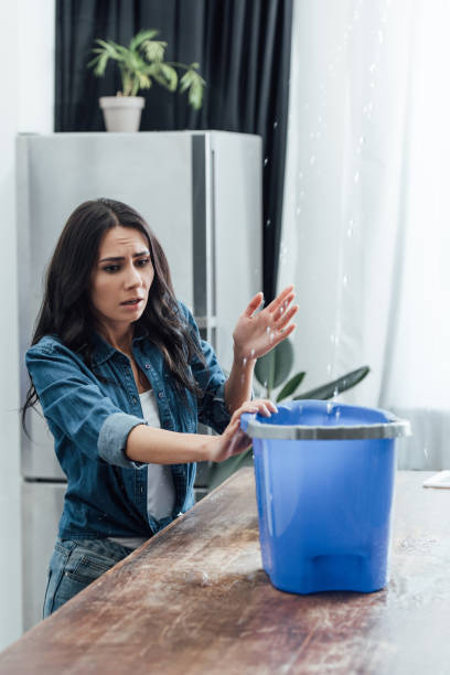 istock Worried woman using bucket during leak in kitchen 1155239644
