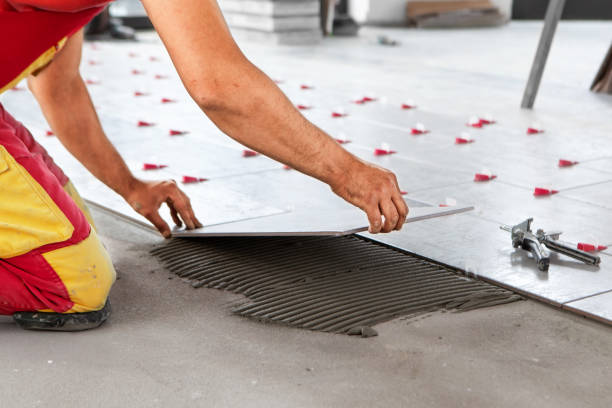 Ceramic Tiles. Tiler placing ceramic wall tile in position over adhesive with lash tile leveling system - Image stock photo