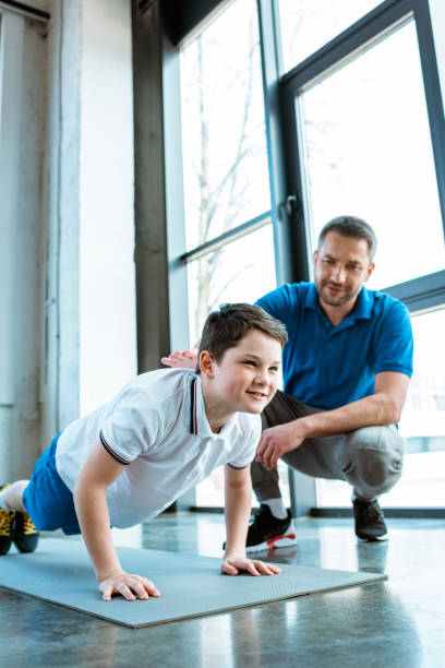 istock father helping son with push up exercise at gym 1155240320