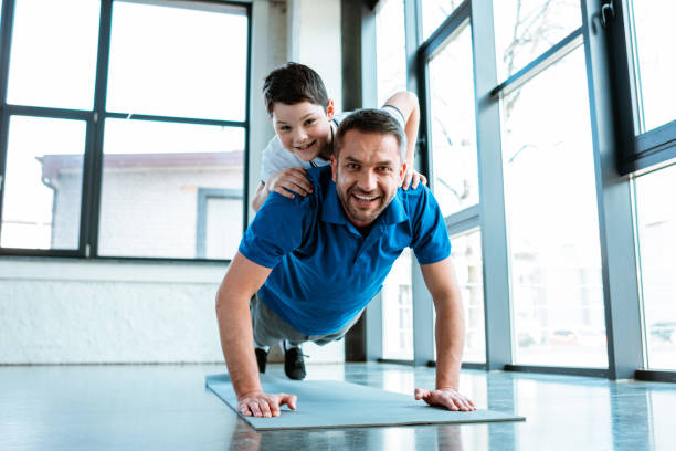 istock happy father doing push up exercise with son on back at gym 1155240321