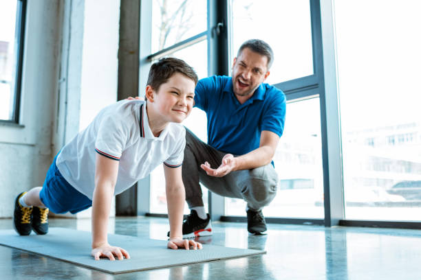 istock father helping son with push up exercise at gym 1155240335