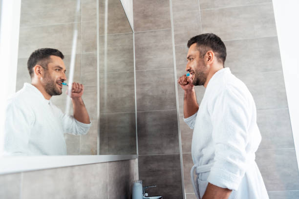 istock handsome man in white bathrobe brushing teeth in bathroom during morning routine 1155240421
