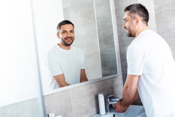 istock handsome smiling man washing hands in bathroom during morning routine 1155240520