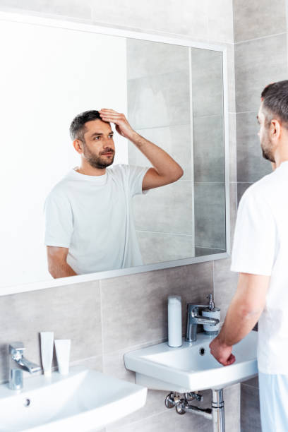 istock handsome man looking at mirror and adjusting haircut in bathroom 1155240523