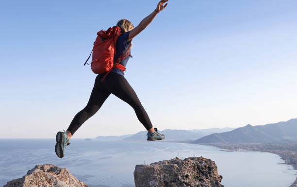 istock Female hiker jumps between rock summits 1155242217