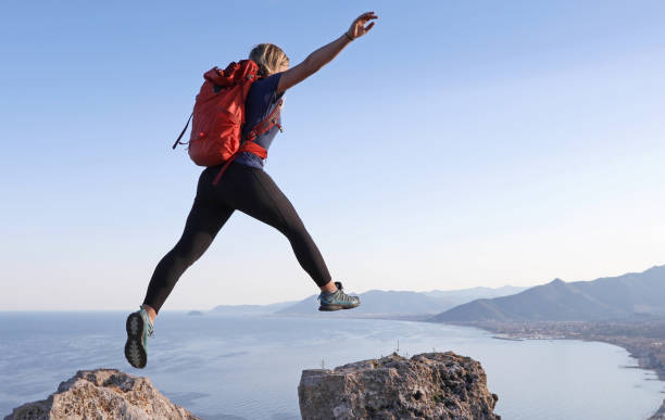 el excursionista femenino salta entre cumbres rocosas - phi fotografías e imágenes de stock