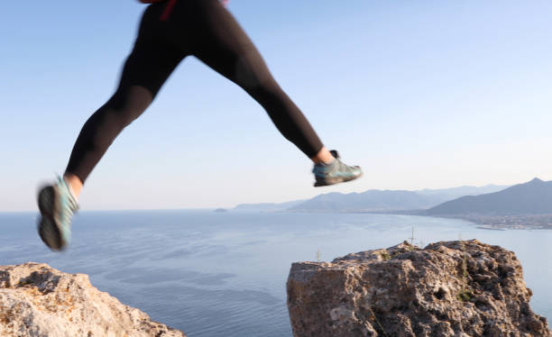istock Female hiker jumps between rock summits 1155242285