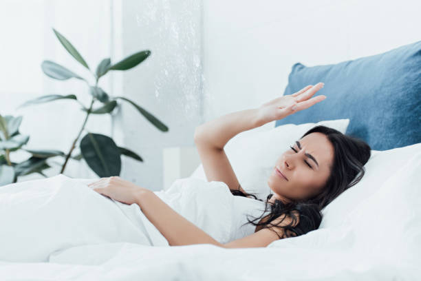 istock Irritated woman lying in bed under leaking ceiling 1155242424