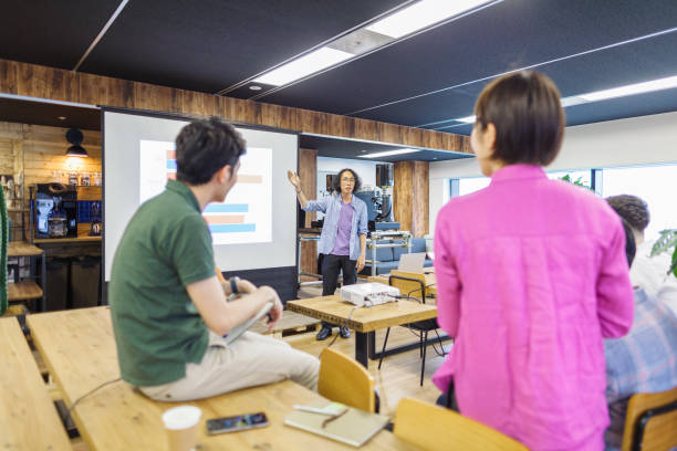A young businessman is giving presentation to his multi-ethnic colleagues.