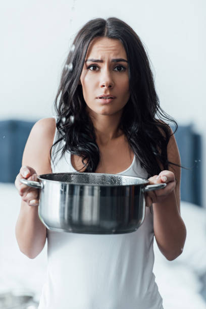 istock Upset young woman holding pot and looking at camera 1155242497