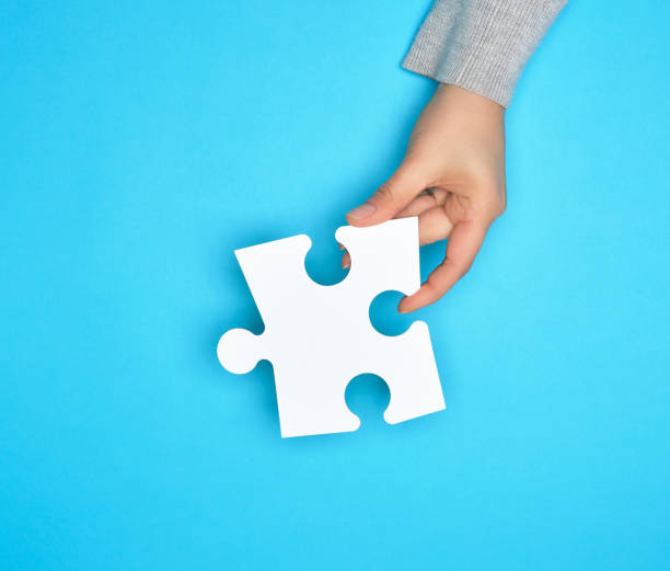 istock female hand holding white empty paper puzzle, blue background 1155244168
