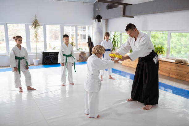 istock Cute blonde-haired boy taking yellow belt from his aikido teacher 1155258480