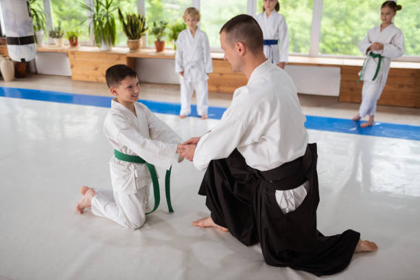 istock Aikido trainer shaking hands of pupil while supporting him 1155258605