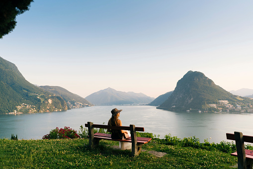 La mujer se relaja sobre el lago y las montañas en el Banco photo