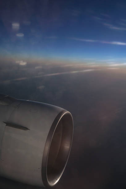 istock Airplane window overlooking the beautiful clouds and the earth. Sunset in flight on vacation. Tourist theme. Stock photo 1155258810