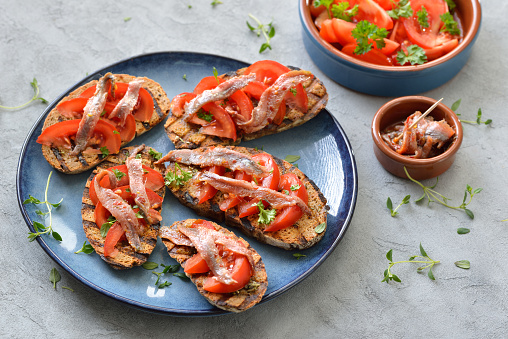 Spanish bar food: Grilled slices of bread with olive oil, herbs, fresh tomatoes and spicy anchovy fillets