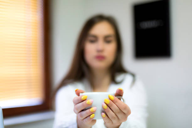 Holding a white mug, an individual enjoys a moment of warmth in their bedroom.