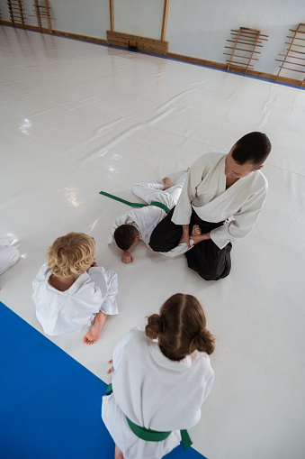 Trainer doing hack. Excited boy and girl looking at their aikido trainer doing hack on boy