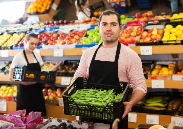 Seller with beans in greengrocery