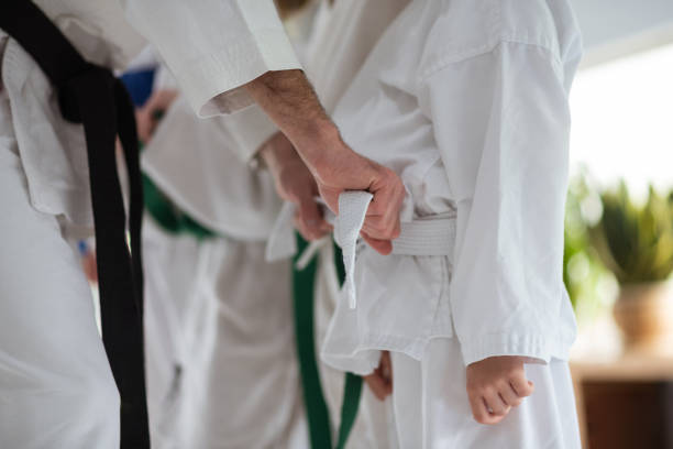 istock Helpful aikido trainer tying belt for his student 1155264076