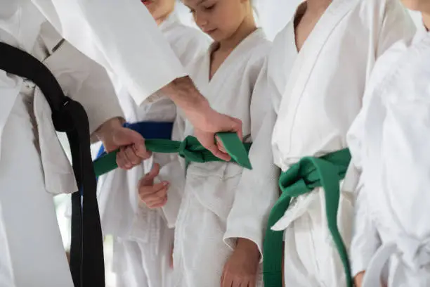 Tying belt. Experienced aikido trainer with black belt tying belt for his pupil before competition