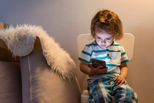 istock Photo of smiling baby boy using smartphone while resting at home 1155264425