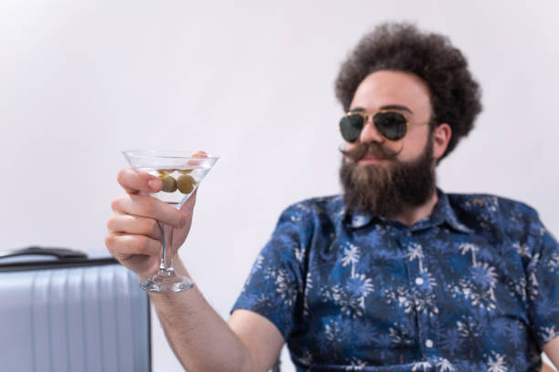 bogaty hipster turysta pijący martini jako orzeźwienie - travel suitcase hawaiian shirt people traveling zdjęcia i obrazy z banku zdjęć