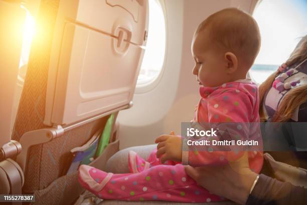 Travelling With Infant Mother And Baby Sitting Together In Airplane Near The Window In Sunny Day Stock Photo - Download Image Now
