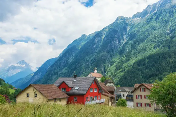 Picturesque residential buildings on the background of high mountains and blue sky with white clouds