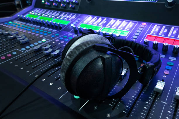 istock Professional audio studio sound mixer console board panel with recording , headphone and adjusting knobs,TV equipment. Blue tone and close-up image with flare light effect. 1155281839